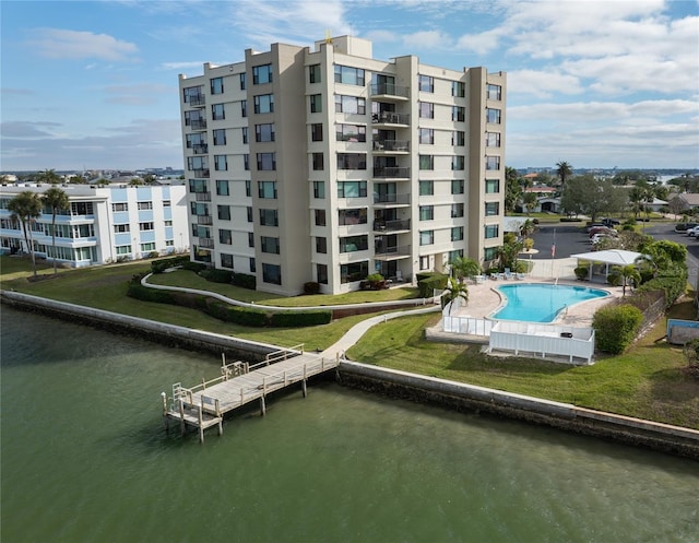 view of building exterior with a community pool and a water view