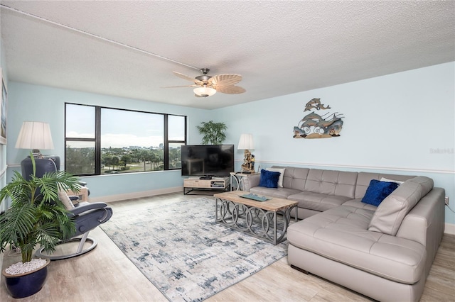 living room featuring ceiling fan, a textured ceiling, and light wood-type flooring