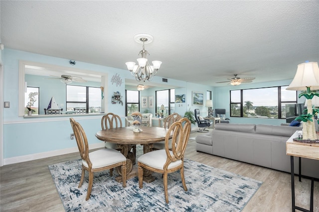 dining room featuring ceiling fan with notable chandelier, light hardwood / wood-style floors, a textured ceiling, and plenty of natural light