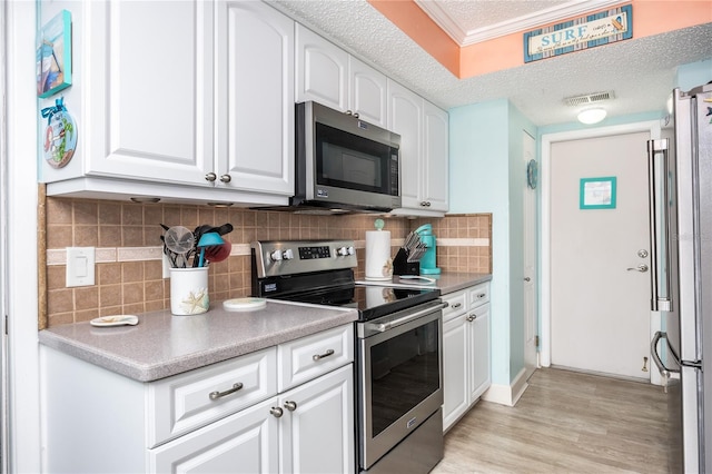 kitchen featuring a textured ceiling, decorative backsplash, white cabinetry, and stainless steel appliances