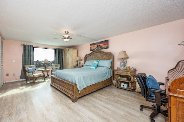 bedroom featuring ceiling fan, light hardwood / wood-style floors, and a textured ceiling