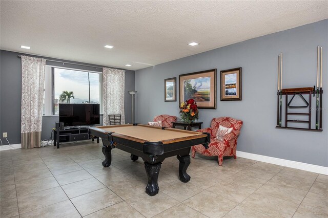 game room with pool table, a textured ceiling, and light tile patterned floors