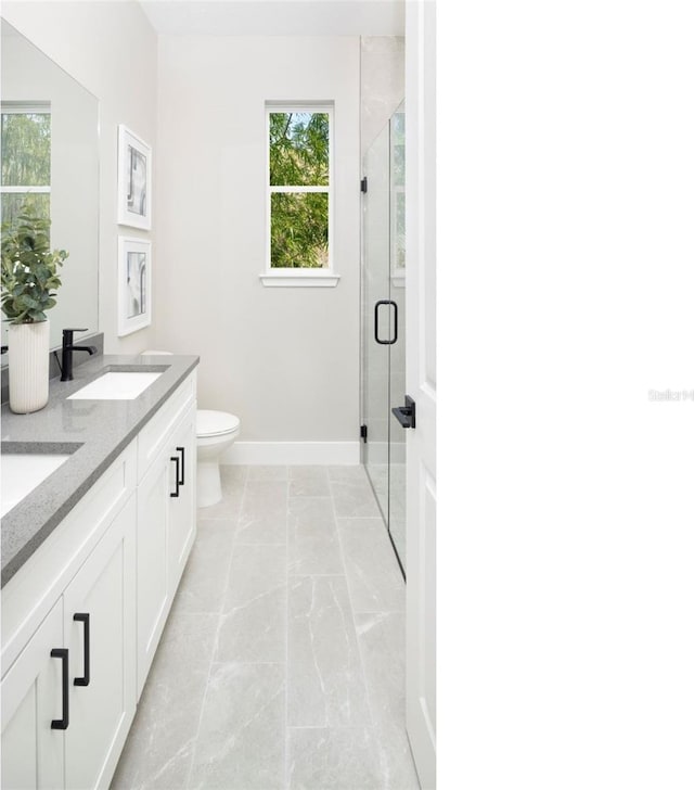 bathroom featuring a wealth of natural light, toilet, a shower with door, and vanity