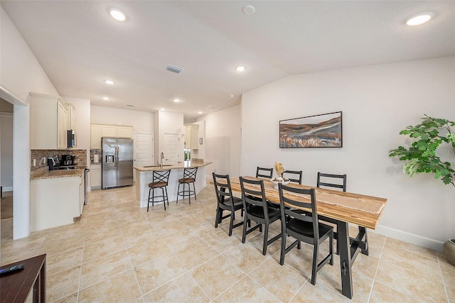 dining area featuring sink, light tile patterned flooring, and lofted ceiling