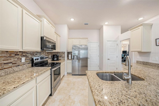 kitchen featuring appliances with stainless steel finishes, sink, light stone counters, light tile patterned flooring, and decorative backsplash