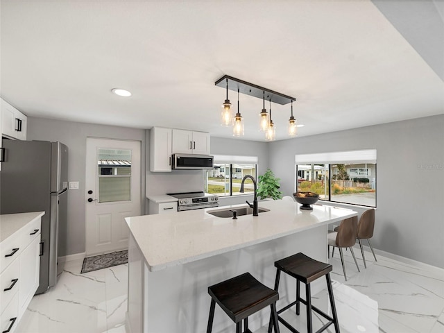 kitchen featuring sink, hanging light fixtures, stainless steel appliances, and a kitchen island with sink