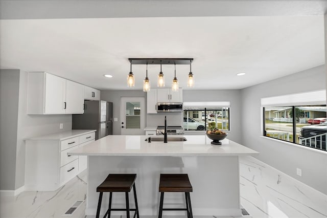 kitchen featuring sink, white cabinetry, pendant lighting, and appliances with stainless steel finishes