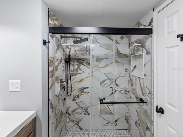 full bath featuring a textured ceiling, a marble finish shower, and vanity