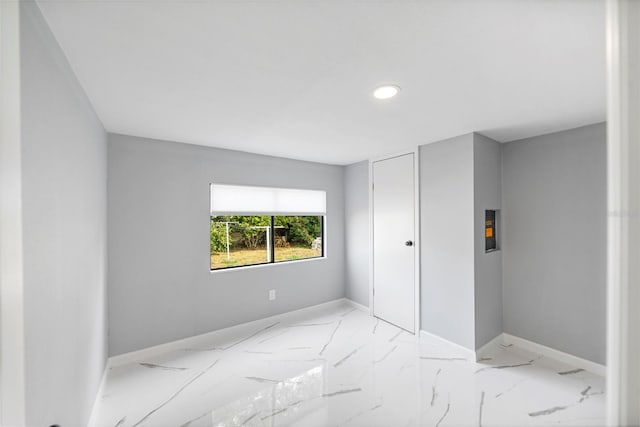 unfurnished bedroom featuring marble finish floor and baseboards