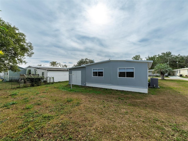 rear view of property featuring a lawn and central air condition unit