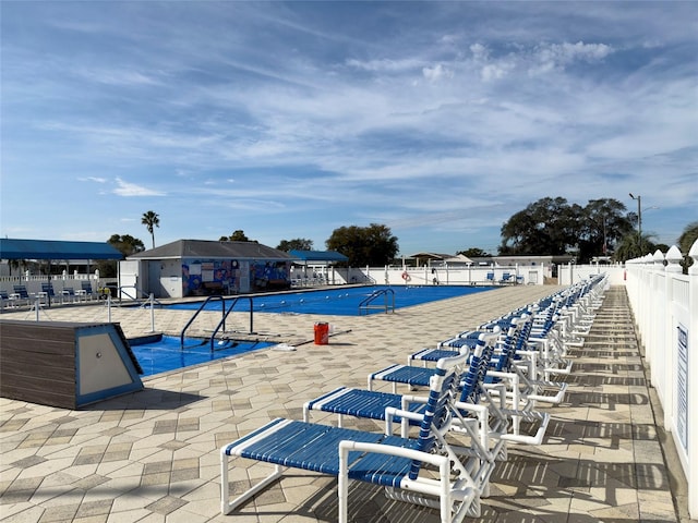 community pool with fence and a patio