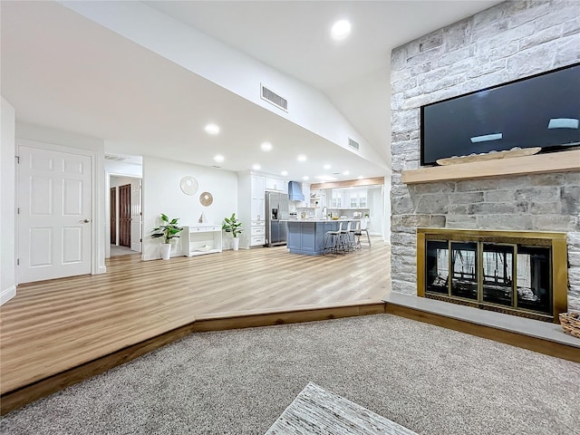 unfurnished living room featuring a fireplace, vaulted ceiling, hardwood / wood-style floors, and sink