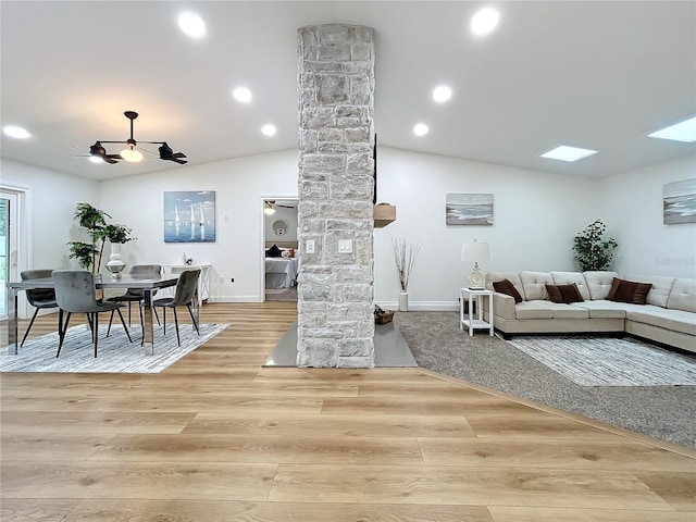 living room with light hardwood / wood-style flooring, decorative columns, ceiling fan, and vaulted ceiling