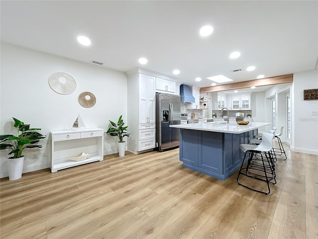 kitchen featuring sink, stainless steel appliances, light hardwood / wood-style floors, white cabinets, and custom exhaust hood