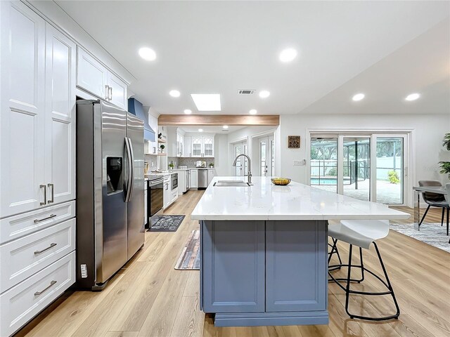 kitchen featuring white cabinetry, a kitchen breakfast bar, an island with sink, and appliances with stainless steel finishes