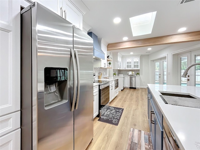 kitchen featuring appliances with stainless steel finishes, beam ceiling, custom range hood, and white cabinets