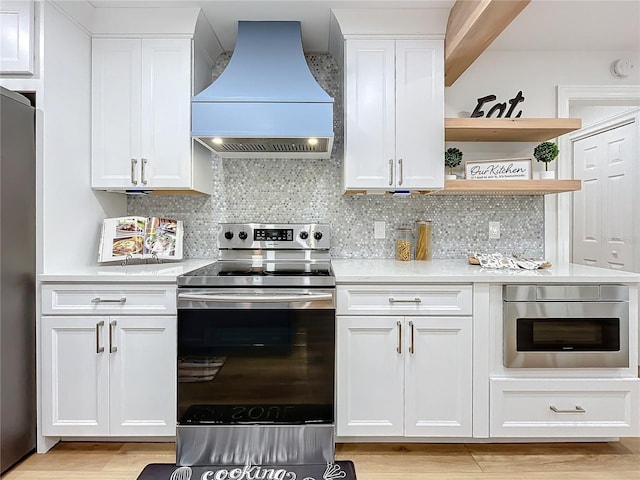 kitchen featuring white cabinetry, custom range hood, and appliances with stainless steel finishes