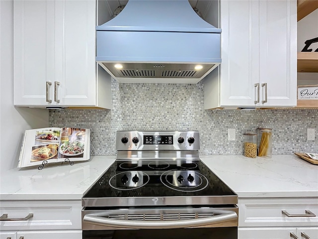 kitchen featuring white cabinetry, custom range hood, stainless steel electric stove, light stone countertops, and decorative backsplash