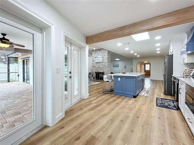 kitchen with sink, stainless steel appliances, an island with sink, a kitchen bar, and light wood-type flooring