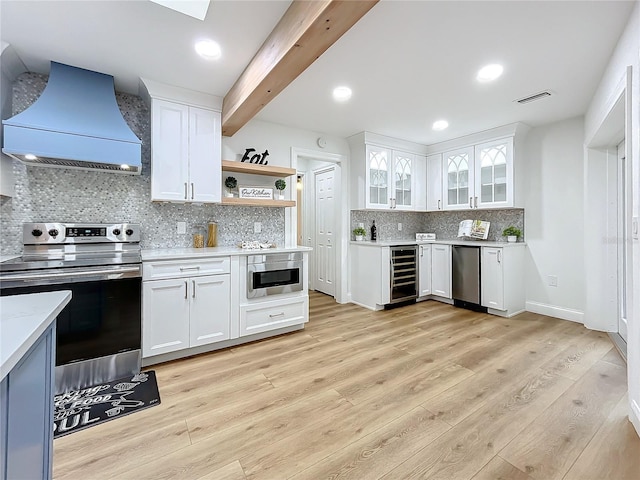 kitchen with appliances with stainless steel finishes, beverage cooler, white cabinets, custom exhaust hood, and beam ceiling