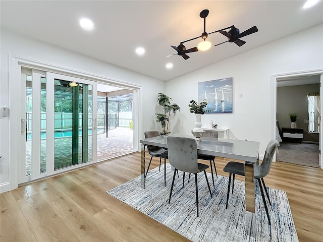 dining space with ceiling fan, lofted ceiling, and light wood-type flooring