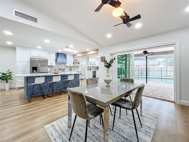 dining room with vaulted ceiling and light hardwood / wood-style flooring