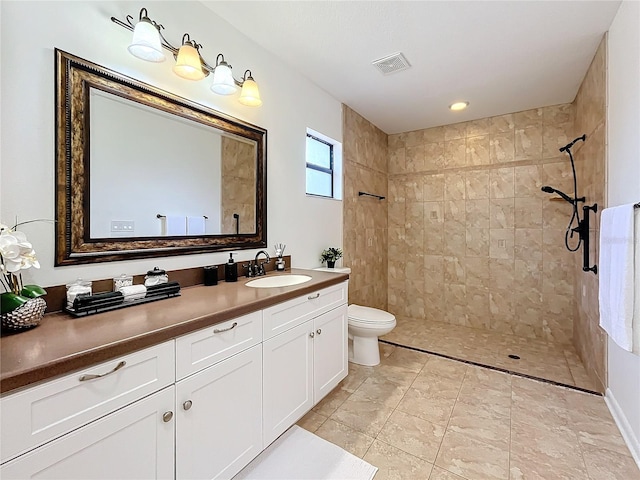 bathroom featuring tiled shower, vanity, and toilet