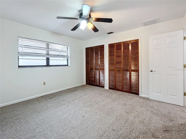 unfurnished bedroom with multiple closets, ceiling fan, and carpet floors