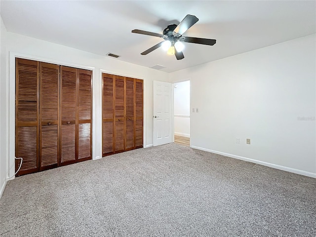 unfurnished bedroom with ceiling fan, carpet floors, and two closets