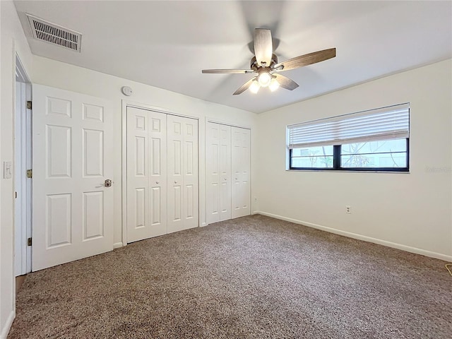 unfurnished bedroom featuring two closets, ceiling fan, and carpet