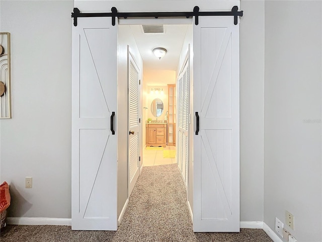 corridor with a barn door and carpet flooring