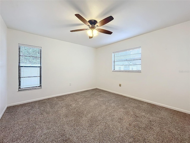 empty room with a wealth of natural light, ceiling fan, and carpet flooring