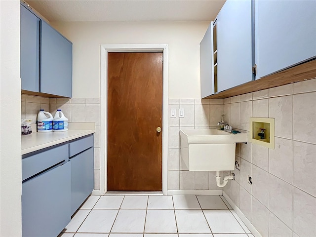 kitchen with blue cabinets, sink, tile walls, and light tile patterned floors