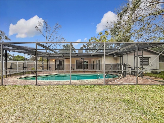 view of pool featuring a lawn, glass enclosure, and a patio area