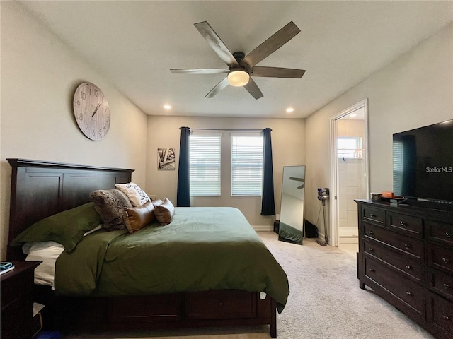 bedroom with multiple windows, ensuite bath, light colored carpet, and ceiling fan