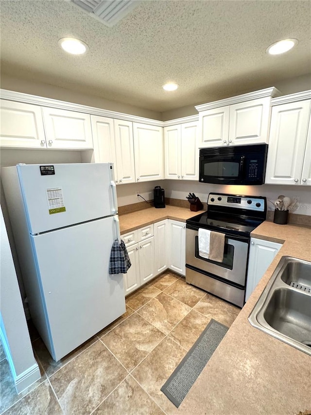 kitchen with white refrigerator, white cabinets, a textured ceiling, and stainless steel electric range