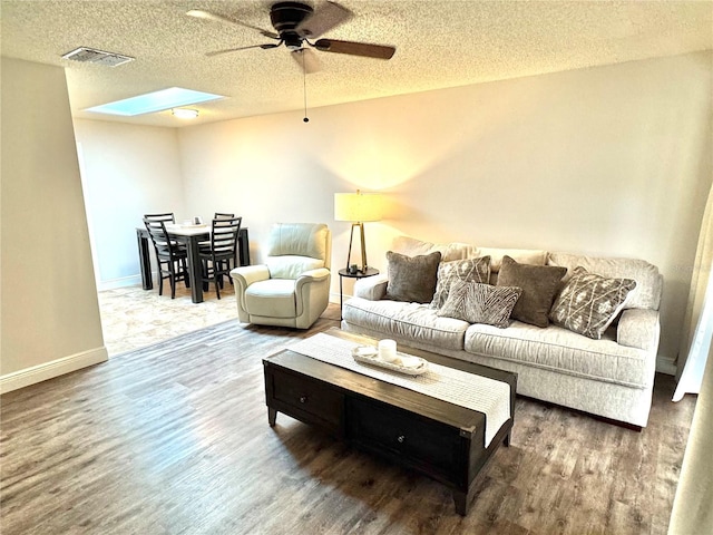 living room featuring a skylight, a textured ceiling, and hardwood / wood-style flooring