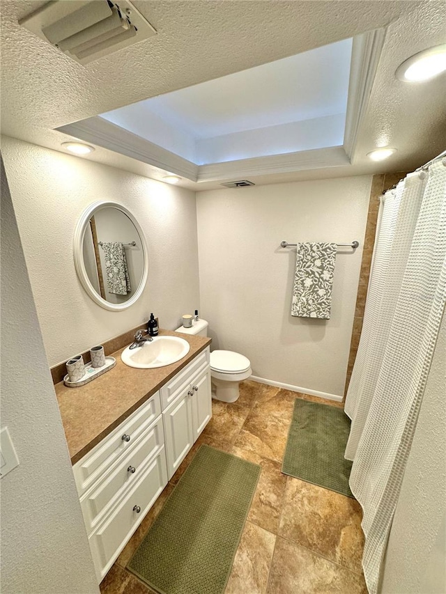 bathroom with vanity, toilet, a raised ceiling, and a textured ceiling