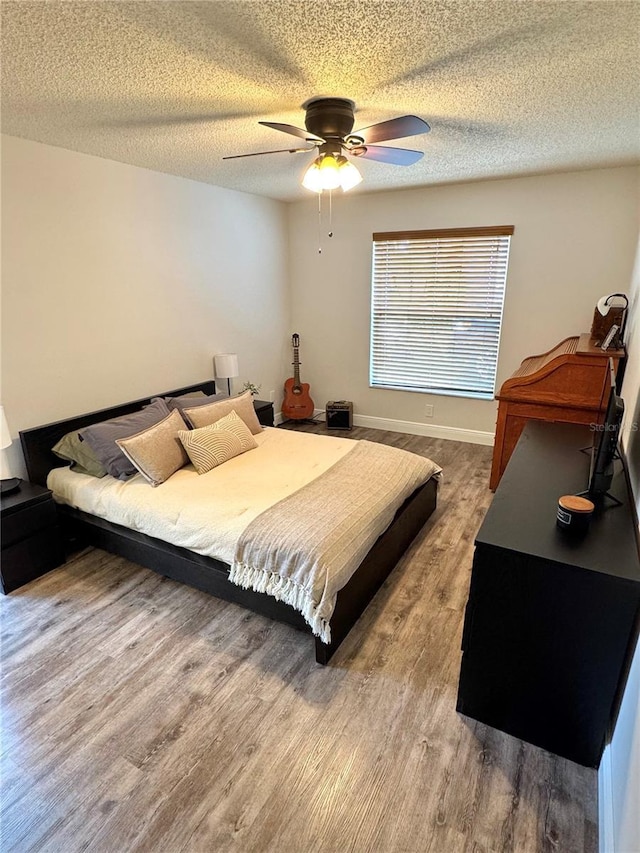 bedroom featuring hardwood / wood-style flooring, a textured ceiling, and ceiling fan