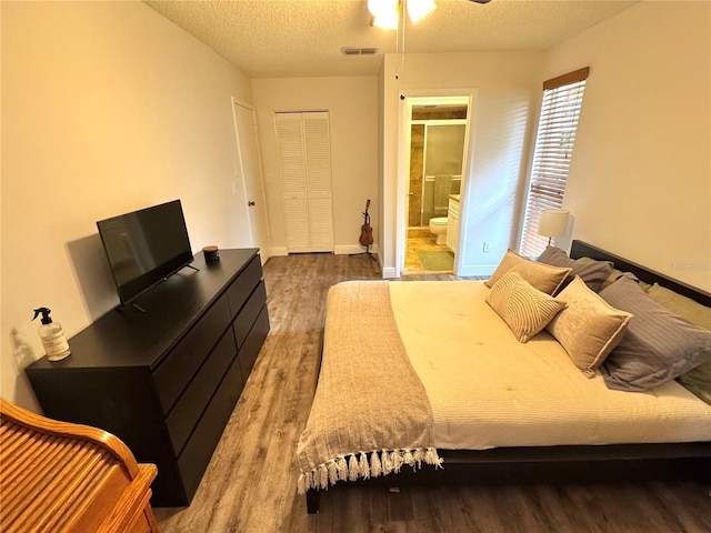 bedroom featuring a closet, hardwood / wood-style floors, a textured ceiling, and ensuite bath