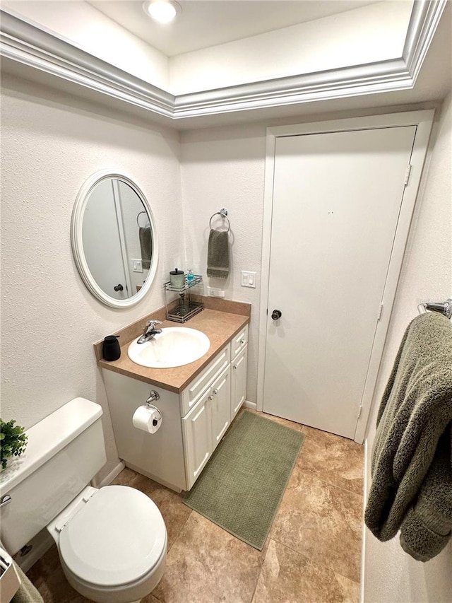 bathroom featuring vanity, toilet, and a tray ceiling