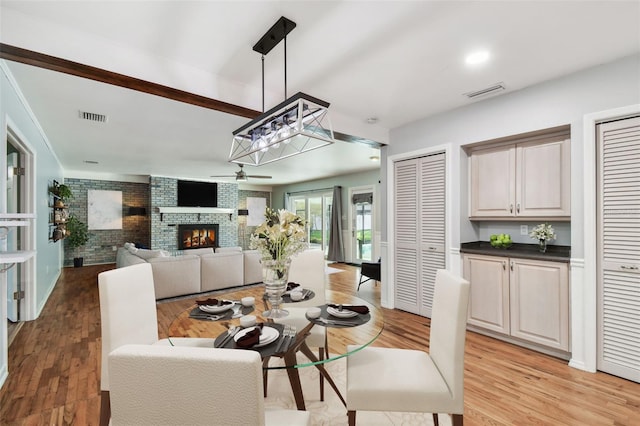 dining room featuring light wood-style flooring, a fireplace, and visible vents