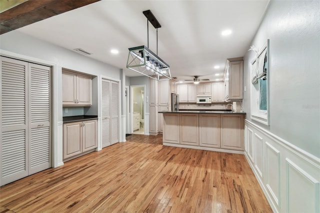 kitchen with visible vents, white microwave, dark countertops, and freestanding refrigerator