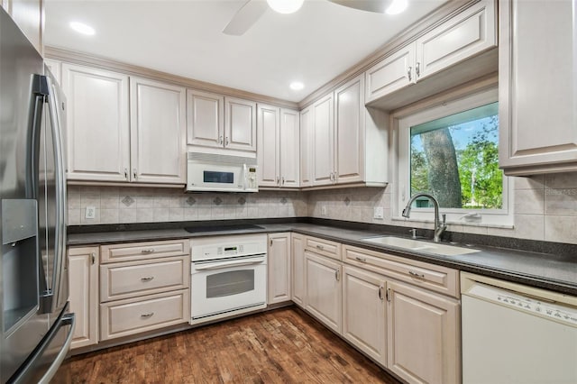 kitchen with dark countertops, white appliances, dark wood-style flooring, and a sink