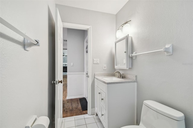 half bath with tile patterned flooring, vanity, and toilet