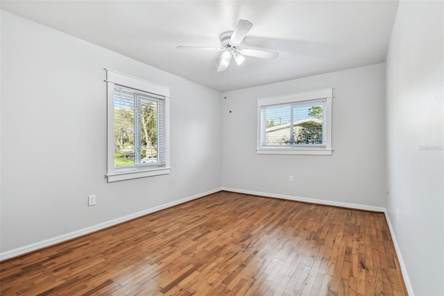 empty room featuring a ceiling fan, baseboards, and hardwood / wood-style floors