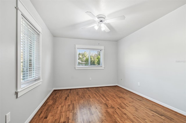 unfurnished room featuring hardwood / wood-style floors, a ceiling fan, and baseboards