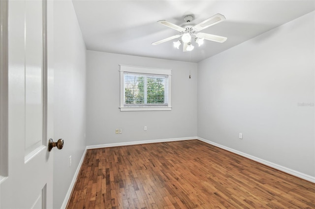 spare room featuring wood-type flooring, baseboards, and a ceiling fan