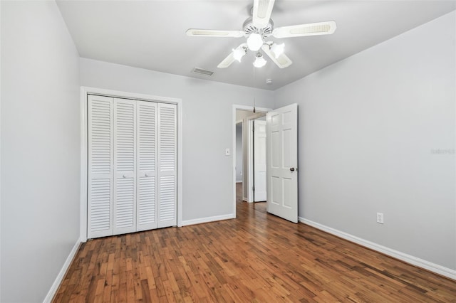 unfurnished bedroom featuring a ceiling fan, a closet, baseboards, and wood finished floors