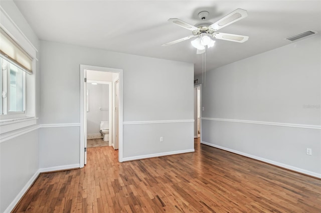 empty room featuring a ceiling fan, baseboards, visible vents, and hardwood / wood-style floors